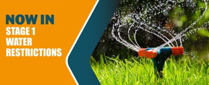 water restrictions text next to sprinklers spraying water on lawn 
